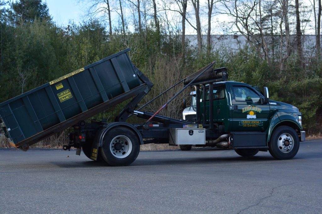 A dumpster being unloaded from a LeBoeuf Rubbish Removal truck.