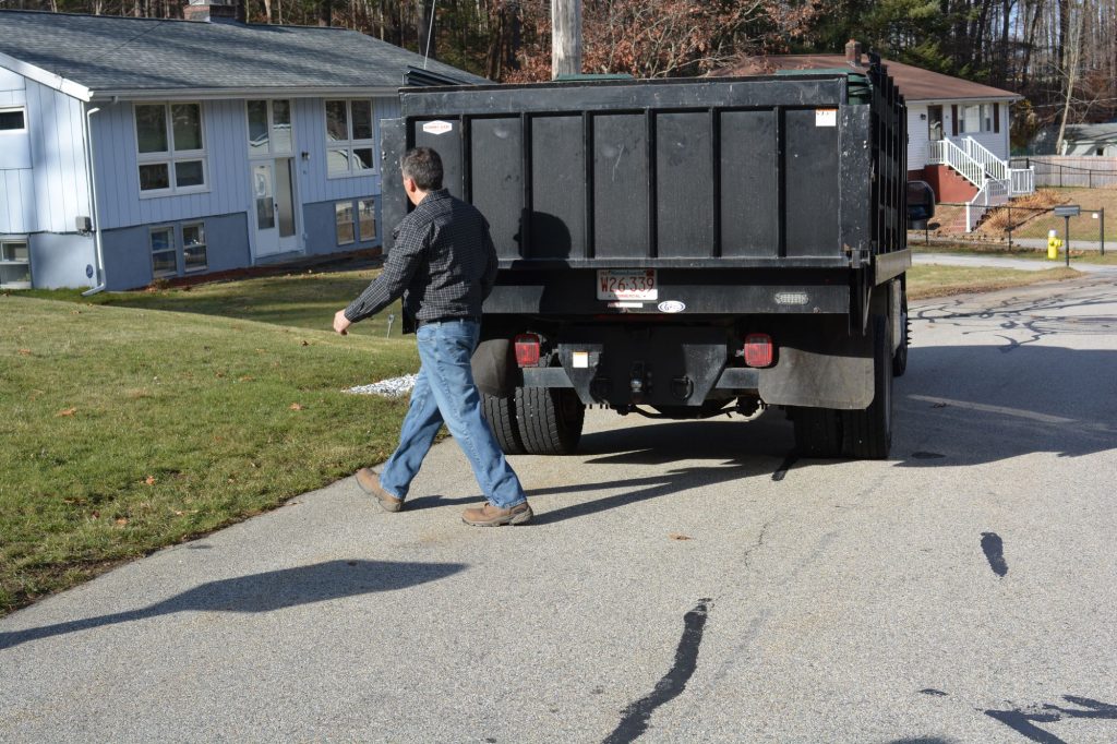LeBoeuf staff member with rack-body truck in residential neighborhood.