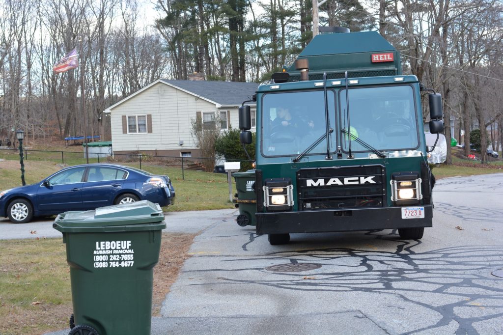 LeBoeuf Rubbish Removal garbage truck pulling up to branded bin in residential neighborhood.