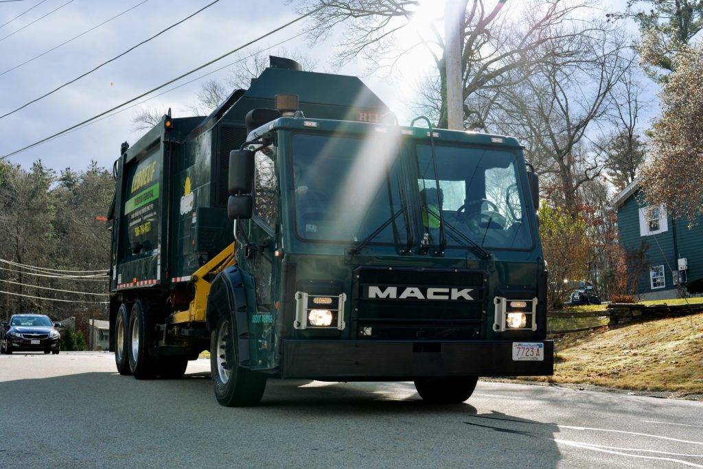 A LeBoeuf garbage truck driving down a residential neighborhood.