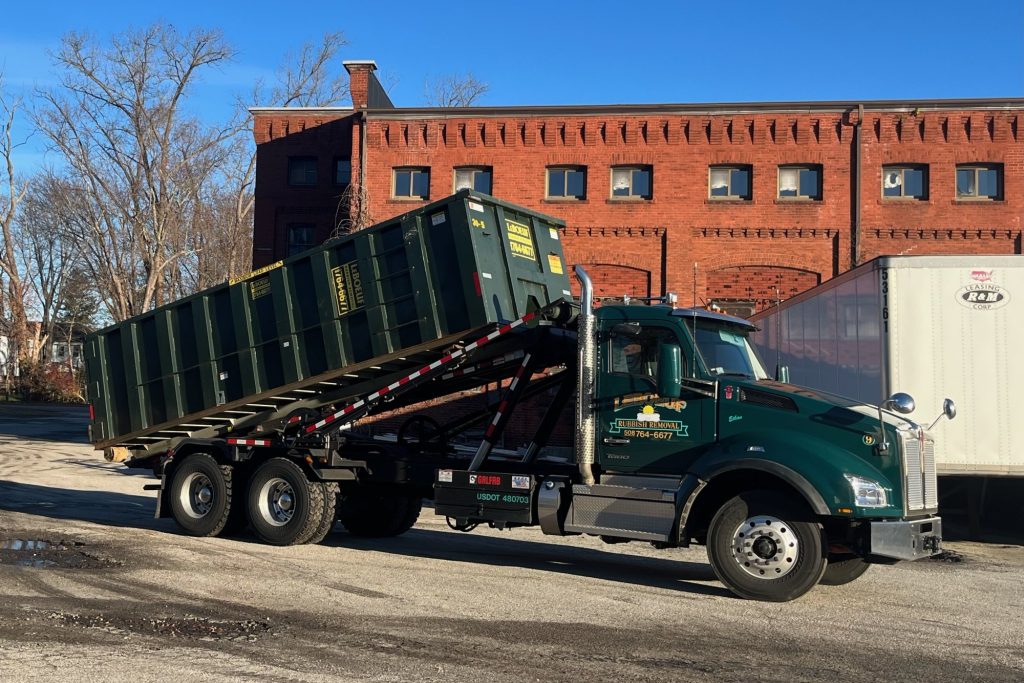 LeBoeuf truck loading a roll off dumpster onto its bed.