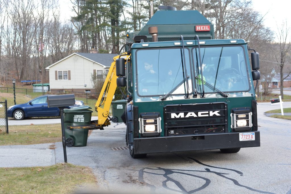 LeBoeuf Rubbish Removal garbage truck picking up a cart in a residential neighborhood.